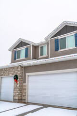 White garage doors at home exterior decorated with wreath and christmas lights