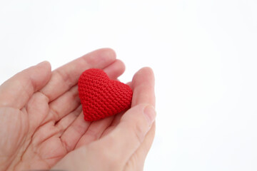 Red knitted heart in female palms of hands against the white snow. Concept of a romantic love, Valentine's day or charity