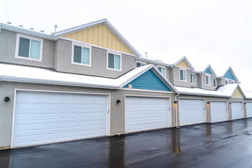 Fototapeta na wymiar White garage doors of apartments along wet road on a cloudy winter landscape