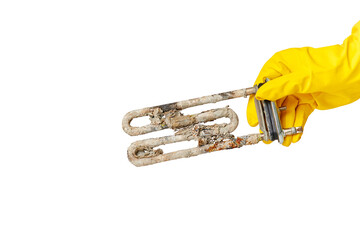 A hand in a yellow glove holds the heating element of a washing machine or dishwasher, covered with...