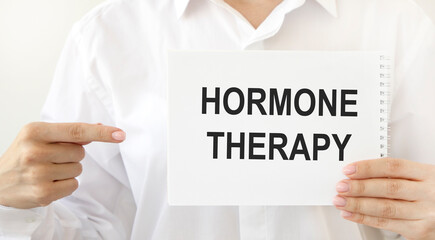 The doctor points to a notebook with the text hormone THERAPY.