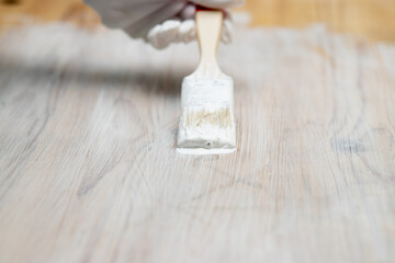 Painting furniture. Gloved hands paint a wooden table with a brush