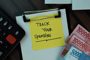 Track Your Spending write on sticky notes with indonesian currency isolated on Wooden Table. Business or Finance concept