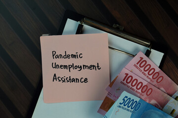 Pandemic Unemployment Assitance write on sticky notes isolated on Wooden Table. Business or Finance concept