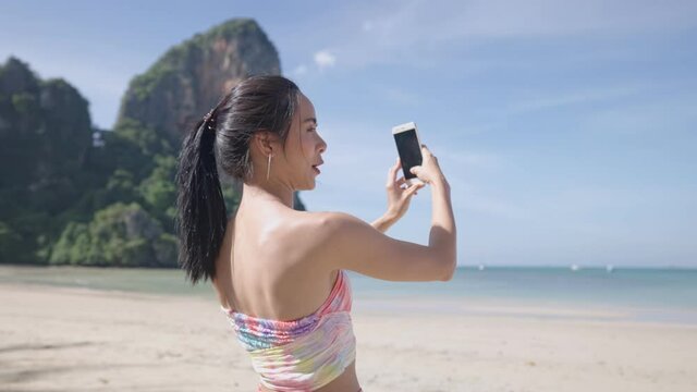 Young asian lady taking snapshot of beautiful ocean scenic view, summer vacation trip, female tourist enjoy island beach, use smartphone taking picture of holiday memories, sunny sea view beach front