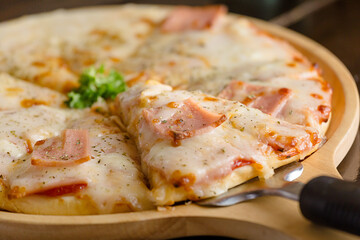 Hot pizza slice with melting cheese on a wooden table..