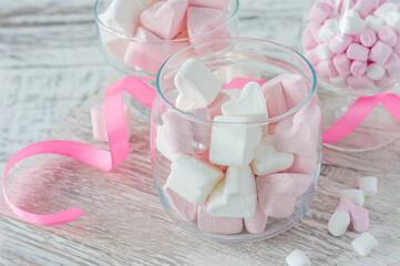Bowl with tasty marshmallows and pink ribbon on white table, closeup