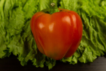 Fresh vegetables, red pepper lies on lettuce leaves on a dark wooden background. Fresh vegetables .