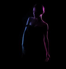 Silhouette of a beautiful woman body on a dark background. Blue and pink light.