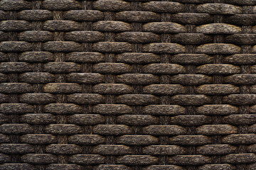 Wicker background made of brown plastic. Rough texture in dark colors. Blank for the designer. Full frame
