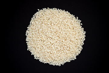 White sesame seeds heap isolated on black background.