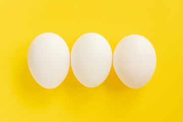Close-up view of raw chicken eggs on yellow background.