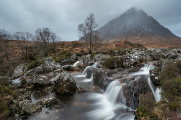 Obraz na płótnie Canvas Epic landscape image of Buachaille Etive Mor waterfall in Scottish highlands on a Winter morning with long exposure for smooth flowing water