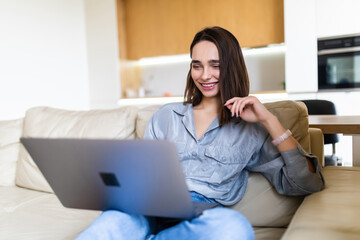 Young woman using a laptop while relaxing on the couch