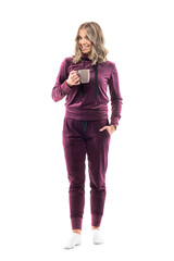 Happy confident young casual woman in leisure wear holding coffee or tea mug smiling at camera. Full body length isolated on white background.