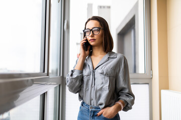 Young woman talking on the phone and looking at window at home