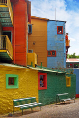 Vertical view of colorful buildings in Caminito of the Argentinean district La Boca, in Buenos Aires, with vintage walls against a blue sky.