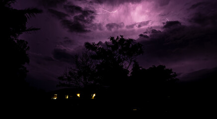 Gothic background with purple storm sky and silhouette of a house