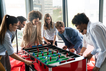 Employees playing table soccer indoor game in the office during break time