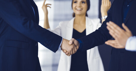 Unknown businesspeople are shaking their hands after signing a contract at meeting, close-up. Business communication concept