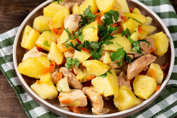 Stewed potatoes with meat. Roast potatoes with pig meat on a ceramic plate on a brown table