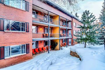 Residential building with red brick wall and balconies overlooking snowy yard