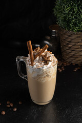 Cocoa with whipped cream, cinnamon sticks and star anise in a transparent mug. A hot drink made of...
