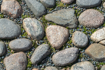 A fragment of a road covered with large cobblestones of various shapes, top view.