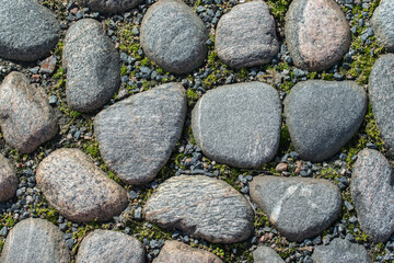 A fragment of a road covered with large cobblestones of various shapes, top view.