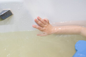 Hand in the bath. The kid bathes in the bath. The baby washes her hands. Hygiene. Bathroom.