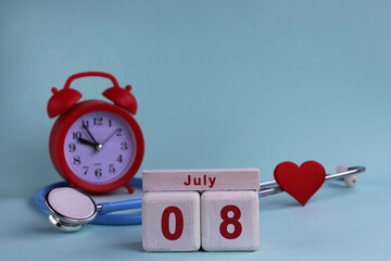 July 8. White wooden calendar blocks with date, clock and stethoscope on blue pastel background. Selective focus. health concept
