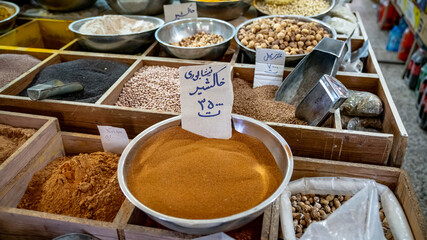 Isfahan, Iran - May 2019: Piles of spices and herbs sold in a traditional Iranian market. Persian writings translate to the names of the herbs in piles.