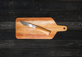 Wooden cutting board and pocket knife on concrete table