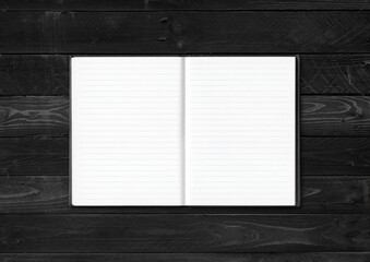 Blank open notebook isolated on black wood background