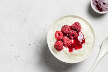 Coconut milk rice pudding in a bowl with frozen raspberry. Top view, space for text.