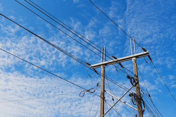 Fototapeta premium bottom view of utility pole under cloudy blue sky