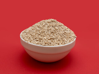 Dry oatmeal in a white bowl on a red background. Breakfast food. Ready to eat.