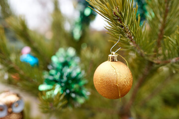 Christmas tree toy orange ball hanging on the fir. Close up, selective focus