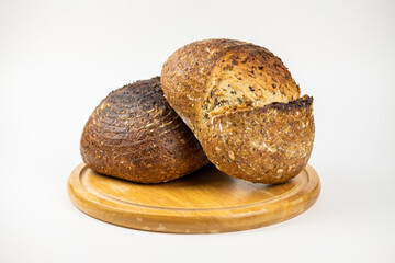 A photo of two homemade bread on a wooden rounded support on a white background