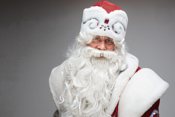 Happy friendly Santa Claus posing on gray studio background with copy space for holiday xmas and new year advertising. High quality photo