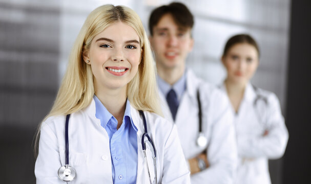 Group of three young doctors standing as a team with arms crossed in modern clinic and ready to help patients. Medicine concept