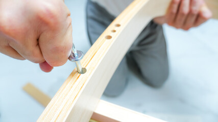 Asian men assemble by tightening the screws of a wooden chair. Furniture assembly concept