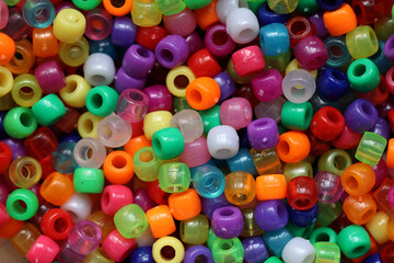 Multicolored plastic beads for handicraft are scattered on the table