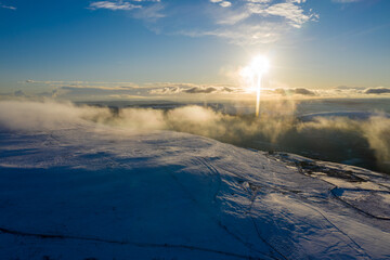 Aerial drone view of snow covered mountains and towns rising above the south east valleys, Wales
