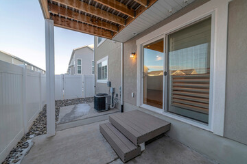 Sliding glass door and wooden steps at the back of a home with wooden fence