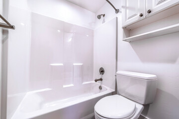 Fototapeta na wymiar Toilet and built in bathtub in side residential bathroom with clean white wall