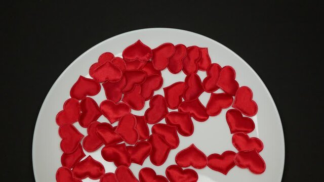Person eating red hearts with fork and knife, Concept of heart killer, heartbreaker, spooner, A lot of hearts on white plate on the black background