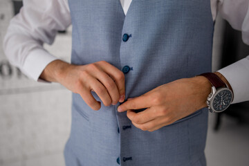 a man buttons up the buttons of a blue suit jacket
