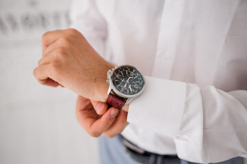 a man puts a watch on his hand in a suit