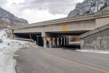 Road and bridge with rocky mountain and cloudy sky in the background in winter
